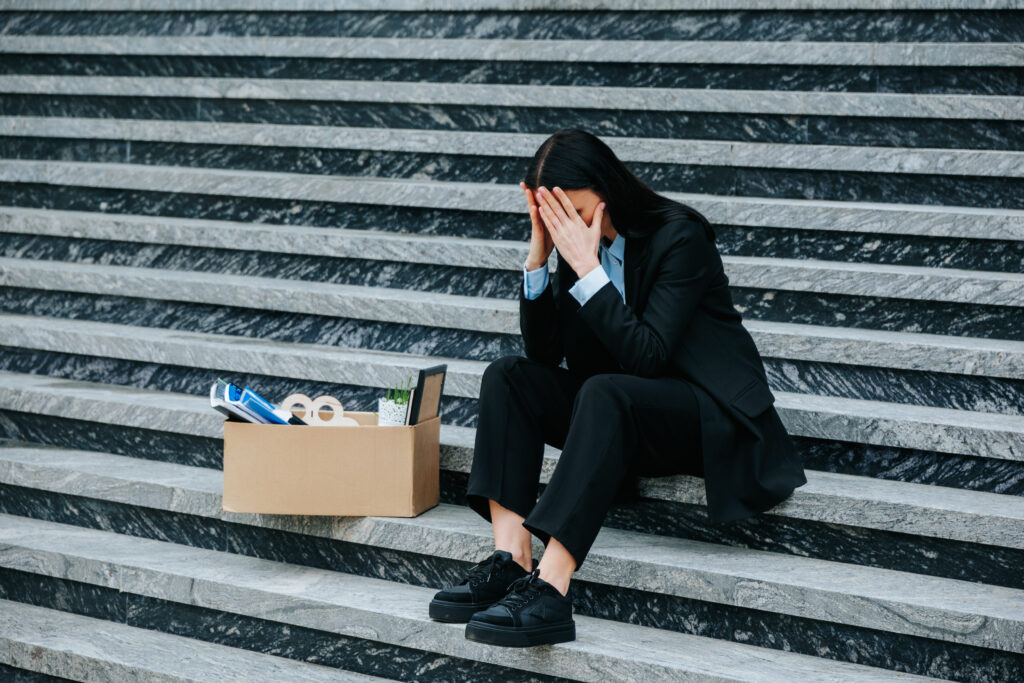 lady sitting on the steps beside a cardboard box with office equipment